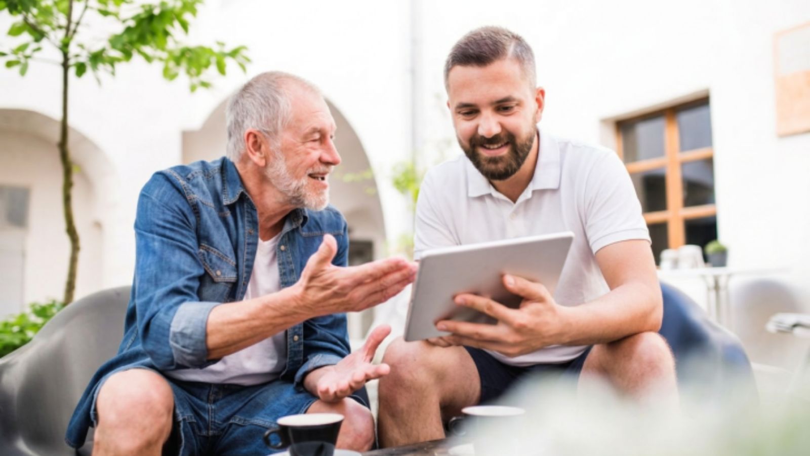 Philip sharing a tablet with an older client on the patio