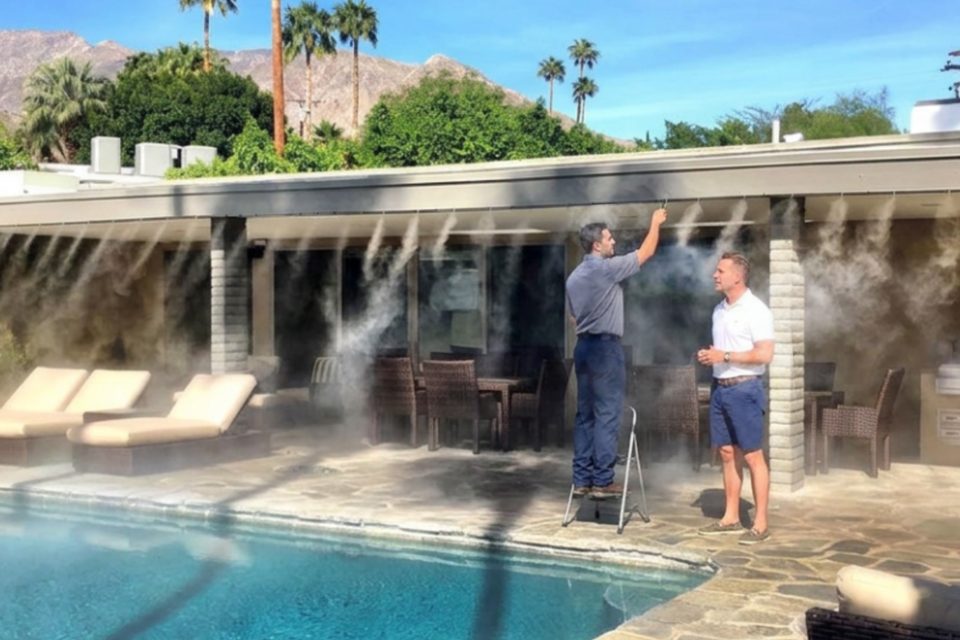 Nicholas and Philip inspecting a patio misting system beside a pool